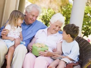 Grandparents with grandchildren on patio with gift smiling